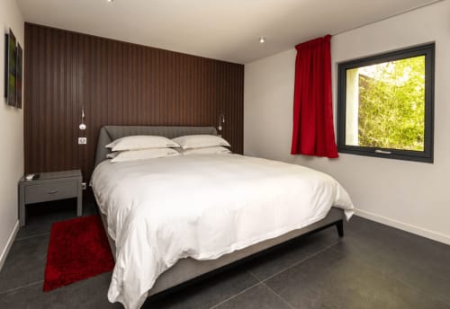 Modern bedroom at Villa Annette in Cassis with sea view, white bedding, dark wood accent wall, and red accents