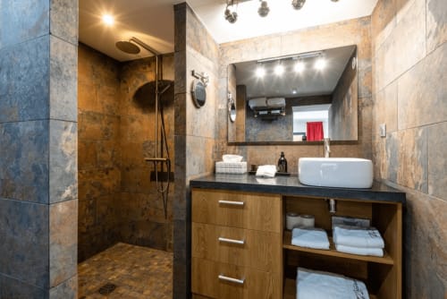 Modern bathroom at Villa Annette in Cassis with walk-in shower, vessel sink, and wood vanity storage