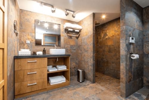 Modern bathroom at Villa Annette in Cassis with slate tile, wooden vanity, vessel sink, and walk-in shower