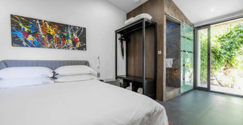 Modern bedroom at Villa Annette, Cassis. Spa room with bed, artwork, wardrobe, and sea view through glass doors.