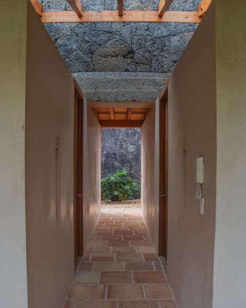 Modern corridor in La Hacienda Tepoztlán Junior Suite leading to garden view with terracotta tile flooring and stone walls