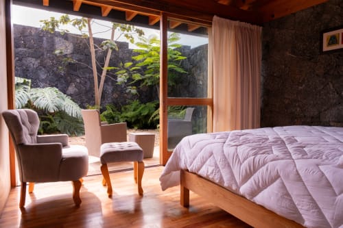 Bright Junior Suite at La Hacienda Tepoztlan with lavender bedding, seating area, wooden beams, and lush garden views through