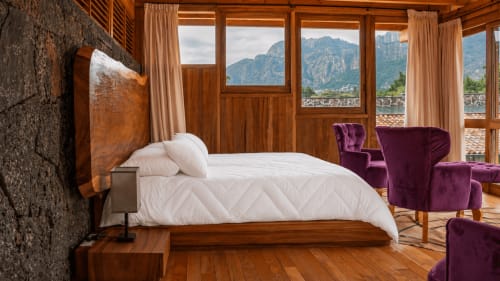 Luxury master suite at La Hacienda Tepoztlán with mountain views, wooden furnishings, white bedding, and purple velvet chairs