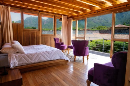 Luxurious master suite at La Hacienda Tepoztlán with mountain views, wooden beams, purple armchairs, and terrace overlooking