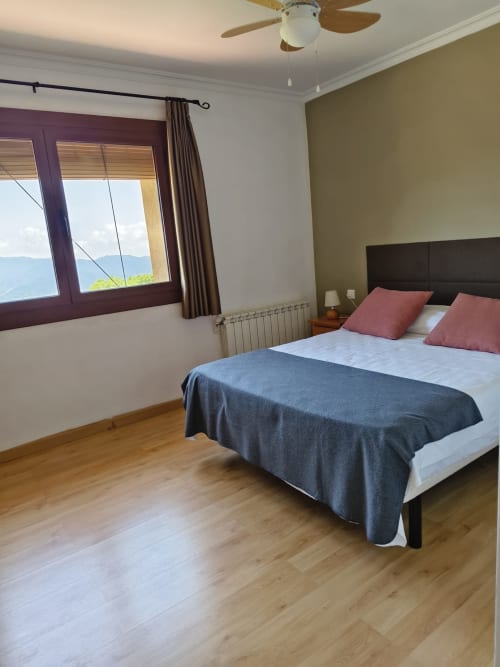 Dormitorio en El Balco del Priorat, Tarragona con cama de matrimonio, vistas a la montaña y suelos de madera