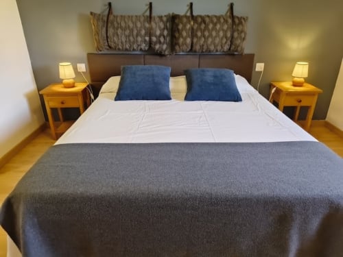 Dormitorio moderno en el hotel El Balco del Priorat en Tarragona con cama doble, almohadas azules, mesitas de noche de madera y ambiente acogedor
