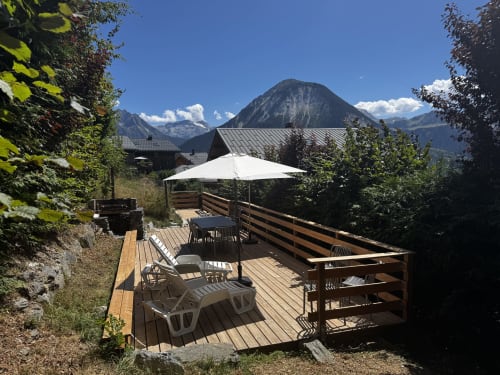 Terrasse de montagne du Chalet école des Cîmes avec transats, parasol et sommets alpins près de Bozel