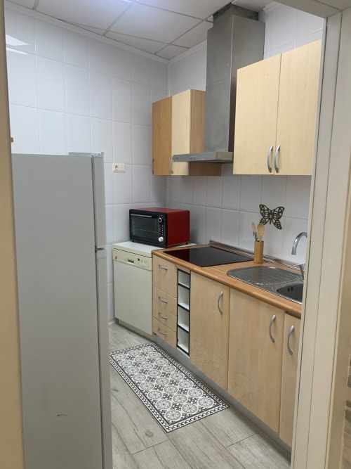 Cocina moderna en el apartamento de lujo Milán Soria, Benidorm, con muebles de madera, electrodomésticos de acero inoxidable y azulejos blancos
