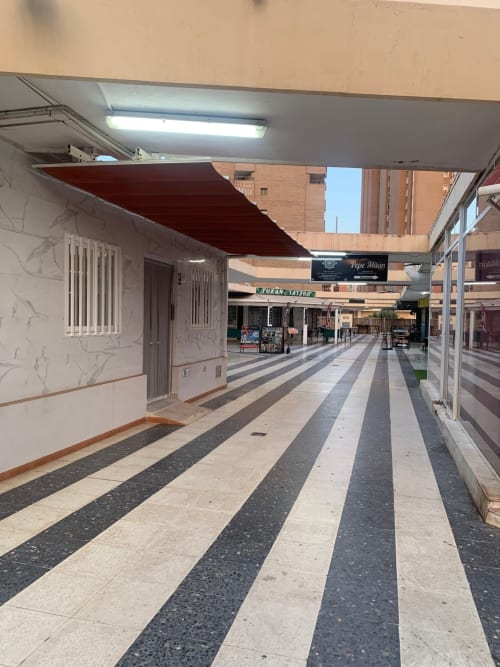 Pasillo de galería cubierta en Benidorm con suelo de rayas que conduce a tiendas en Milán Soria Luxury