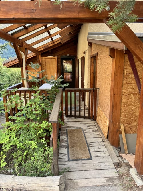 Entrée en passerelle bois des Chalets La Caillaude, appartement duplex à La Salle-les-Alpes, avec pergola et vue sur les montagnes