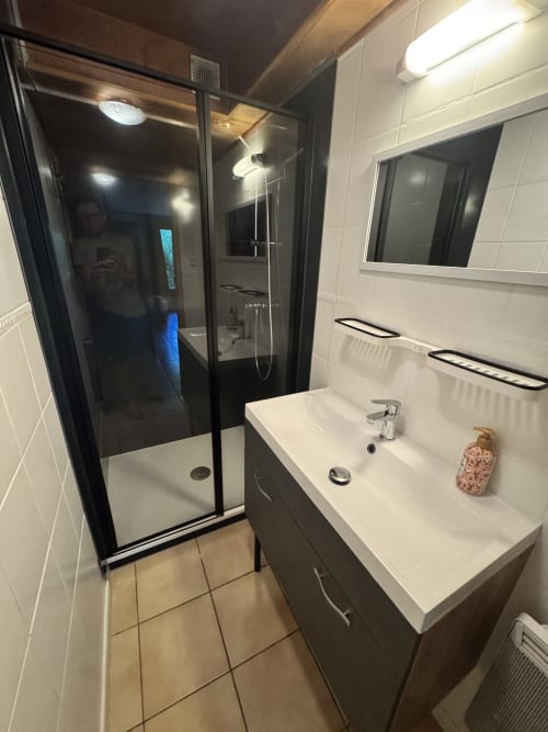Salle de bain moderne de l'appartement La Guisane aux Chalets La Caillaude avec douche, lavabo et sèche-serviettes électriques