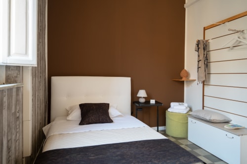 Modern bedroom at I colori della Sicilia in Caltagirone with cream headboard, brown accent wall, and garden views