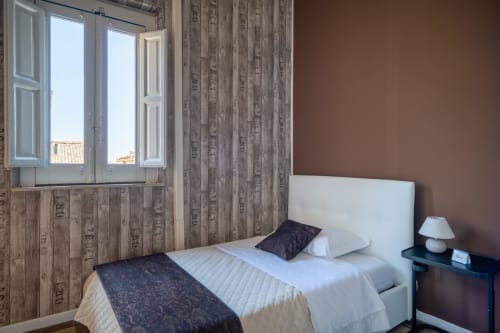 Cozy bedroom at I colori della Sicilia in Caltagirone with white bed, wood-patterned walls, and garden views through window