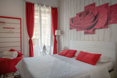 Modern bedroom with red and white decor, rose artwork, and garden views at Rosa room in Caltagirone, Sicily