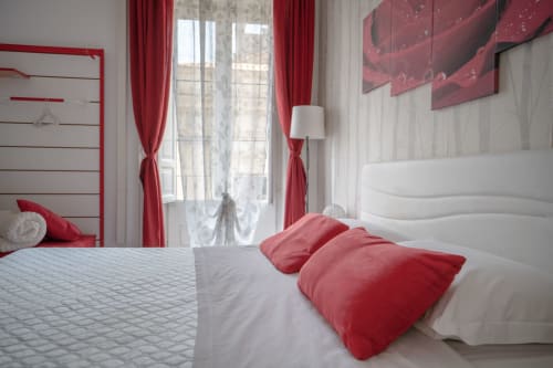 Elegant bedroom at I colori della Sicilia in Caltagirone with red and white décor, red curtains, and landmark views