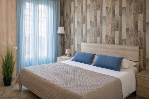 Modern bedroom at I colori della Sicilia in Caltagirone with wooden accent wall, blue pillows, and garden view from balcony