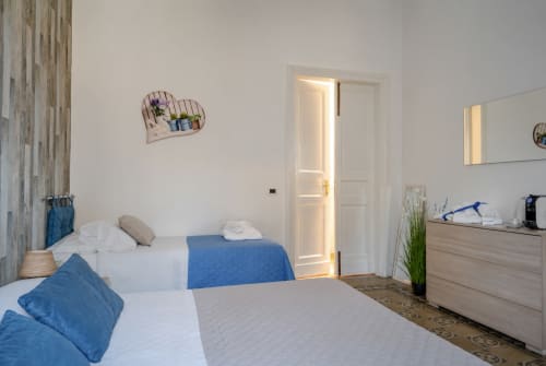 Bright bedroom with twin beds, blue accents, and en-suite bathroom at Lavanda room, I colori della Sicilia B&B in