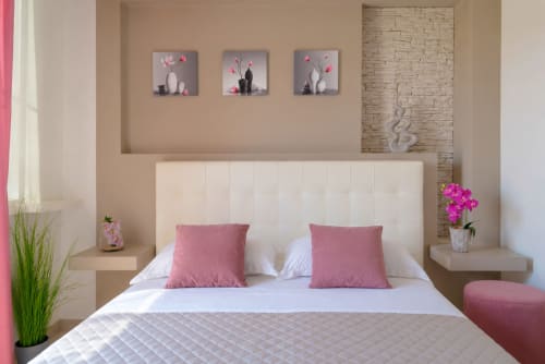 Modern bedroom at Orchidea B&B in Caltagirone with white upholstered bed, pink cushions, and floral wall art