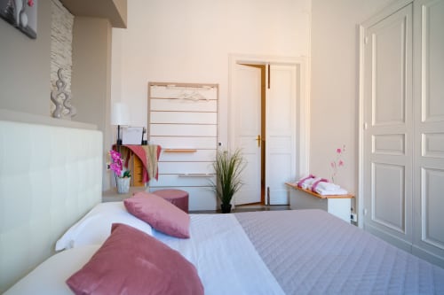 Bright modern bedroom at Orchidea, I colori della Sicilia in Caltagirone with pink bedding, white wardrobe, and landmark