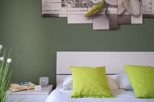 Modern bedroom with green accent wall, white bed with lime pillows, and landmark view at Giglio room, Caltagirone Sicily