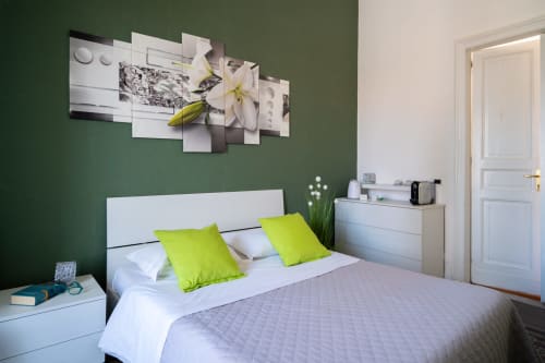 Bright bedroom with green walls, white bed, lime pillows, modern artwork, and landmark view at I colori della Sicilia B&B in