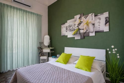 Modern bedroom at I colori della Sicilia in Caltagirone with white bed, lime green pillows, green accent wall, and floral