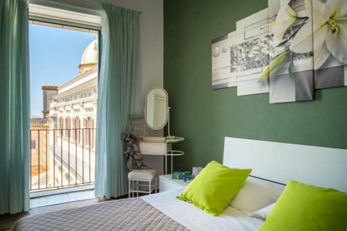 Bright bedroom at I colori della Sicilia, Caltagirone with green walls, lime pillows, balcony view of landmark cathedral