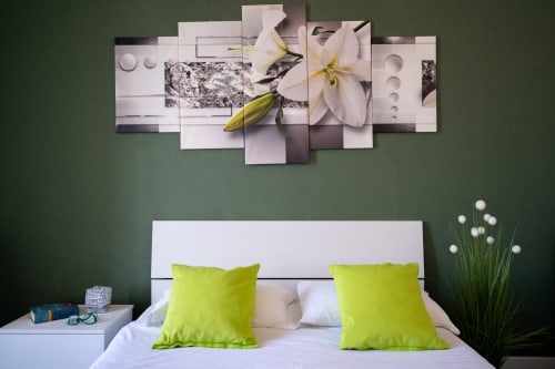 Modern bedroom at I colori della Sicilia with white bed, lime green pillows, and artistic floral wall art in Caltagirone,