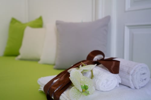 Rolled white towels tied with brown ribbon and green washcloths in Giglio room at I colori della Sicilia B&B, Caltagirone