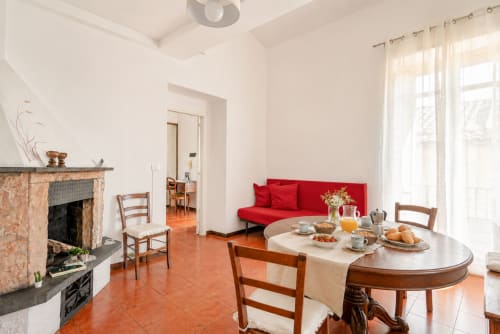 Luminosa sala da pranzo nell'appartamento La Tegola, I colori della Sicilia a Caltagirone, con divano rosso, pavimenti in cotto e camino