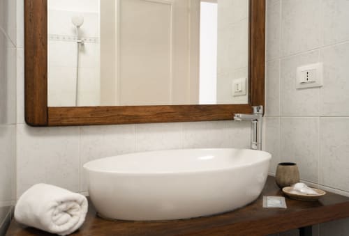 Moderna vasca ovale bianca con piano in legno e specchio nel lussuoso bagno di I colori della Sicilia, Caltagirone