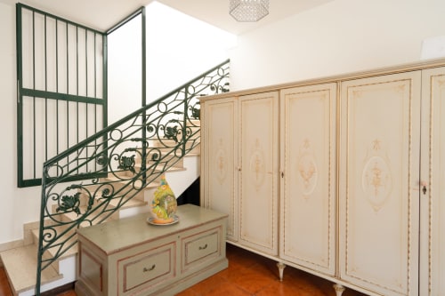Elegante appartamento siciliano con armadio ornamentale, scalinata decorativa e pavimenti in cotto a I colori della Sicilia