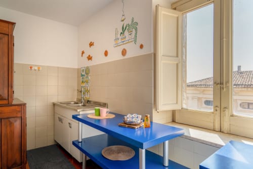 Luminosa cucina siciliana con bancone blu, lavello, piastrelle tradizionali e decori in terracotta a I colori della Sicilia
