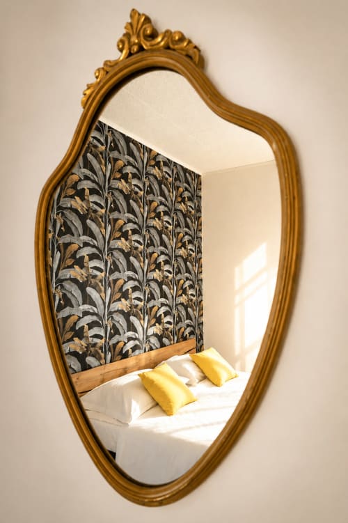 Specchio dorato ornamentale che riflette il letto con cuscini gialli nella camera La Tegola di I colori della Sicilia, Caltagirone