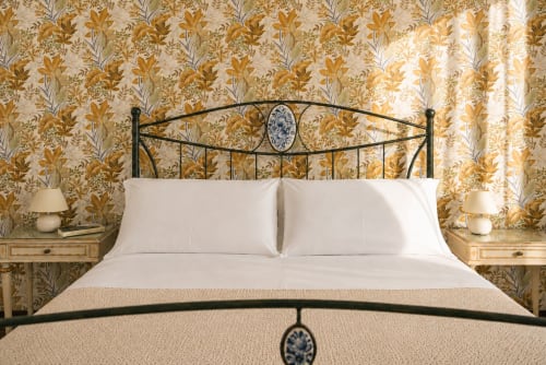 Camera elegante all'I colori della Sicilia di Caltagirone con carta da parati floreale elaborata, letto in ferro battuto e biancheria bianca