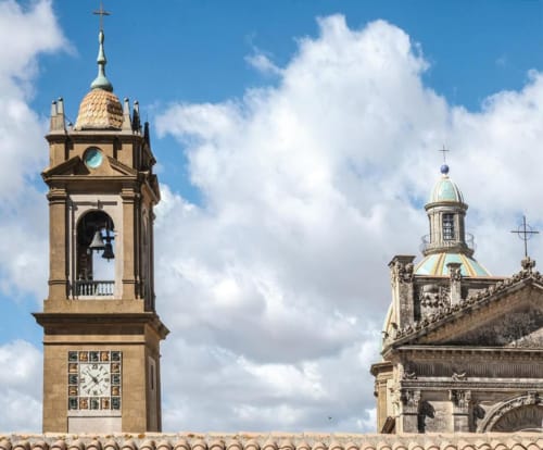 Campanile con orologio e cupola della chiesa storica di Caltagirone contro il cielo azzurro