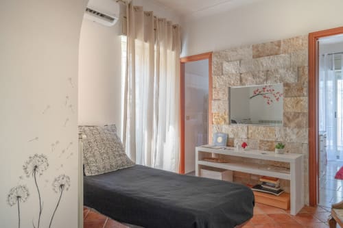 Bedroom in Il sogno apartment at I colori della Sicilia B&B, Caltagirone, with bed, vanity with TV, stone accent wall, and