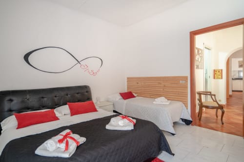 Superior apartment bedroom at I colori della Sicilia in Caltagirone with two beds, black headboard, red pillows, and wooden