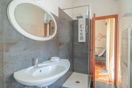 Modern bathroom in Il sogno apartment at I colori della Sicilia, Caltagirone with round mirror, white sink, and walk-in