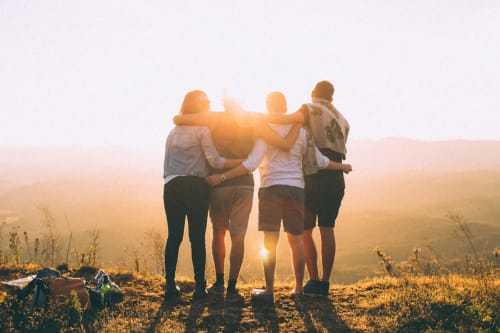 Cuatro amigos abrazándose al atardecer en Lyon, celebrando la camaradería en el albergue Yasi