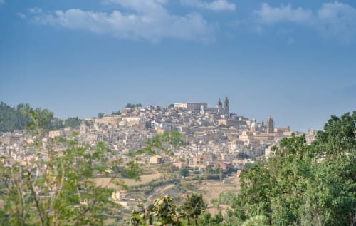 Caltagirone hilltop cityscape with terracotta buildings and churches under blue sky