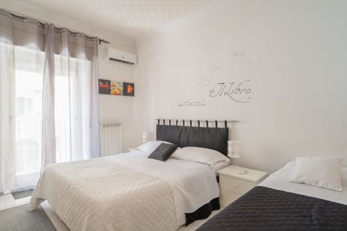 Bright bedroom at I colori della Sicilia B&B in Caltagirone, Sicily with twin beds, black headboard, and wall art reading