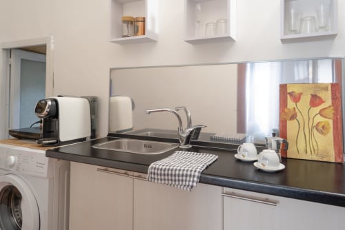 Modern kitchenette in Il sogno apartment at I colori della Sicilia, Caltagirone, with black countertop, appliances, and