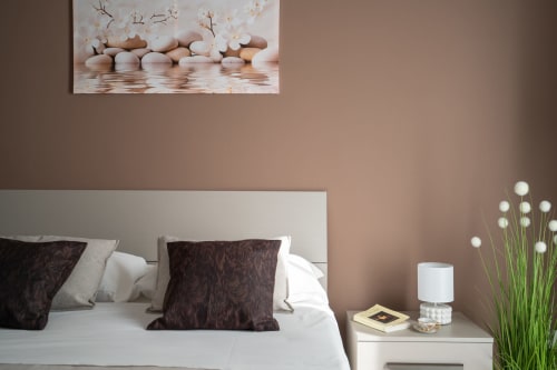 Elegant bedroom at I Colori della Sicilia in Caltagirone with neutral tones, white bed, dark pillows, and serene wall art