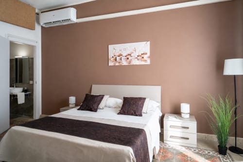 Diamante room at I Colori della Sicilia in Caltagirone with terracotta walls, white bed, dark pillows, modern amenities, and