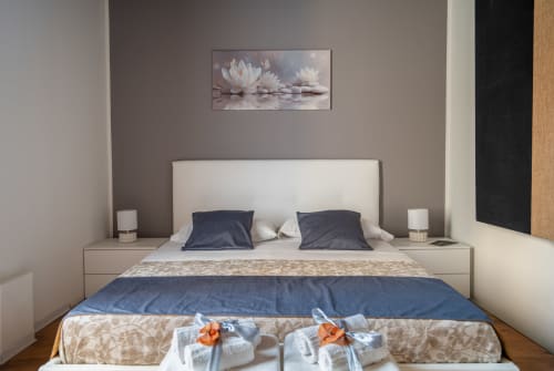 Elegant bedroom at I colori della Sicilia B&B in Caltagirone with cream upholstered bed, navy pillows, and lotus flower