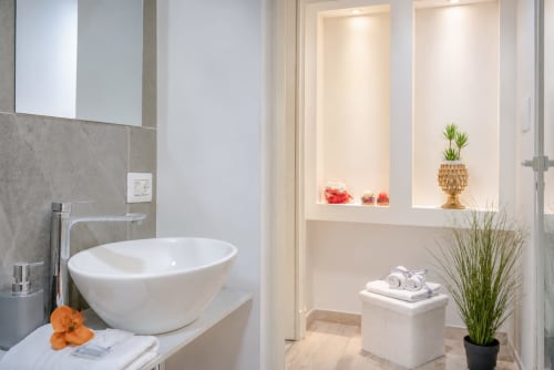 Modern bathroom in Perla room at I Colori della Sicilia B&B, Caltagirone, with white oval sink, gray tilework, and decorative