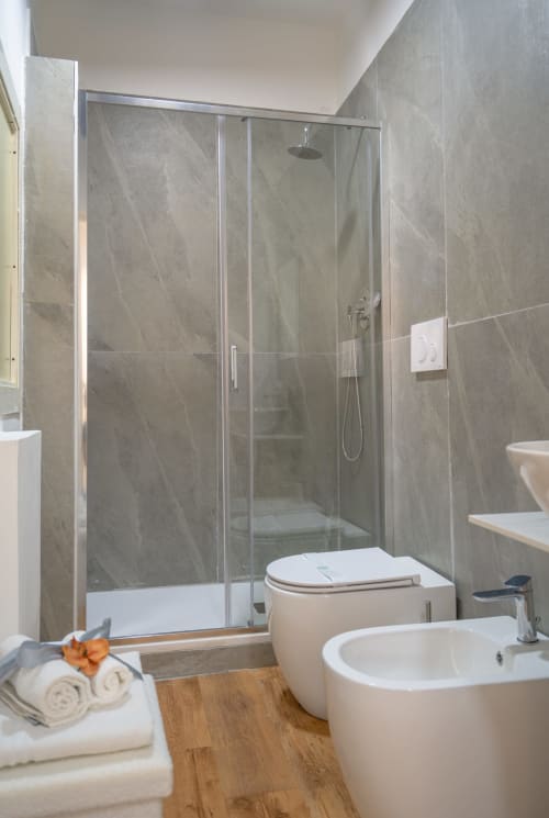 Modern bathroom at I colori della Sicilia with glass shower enclosure, white sink, and wooden flooring in Caltagirone
