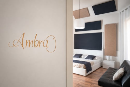 Camera Ambra presso I Colori della Sicilia B&B a Caltagirone con camera da letto moderna, dettagli nero e beige, e divano in pelle nera
