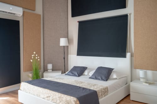 Modern bedroom at I colori della Sicilia in Caltagirone with white bed, dark headboard TV, and cork accent walls